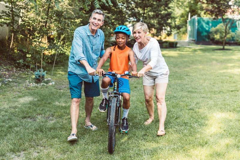 Male and female caregiver with preteen learning to ride a bike.