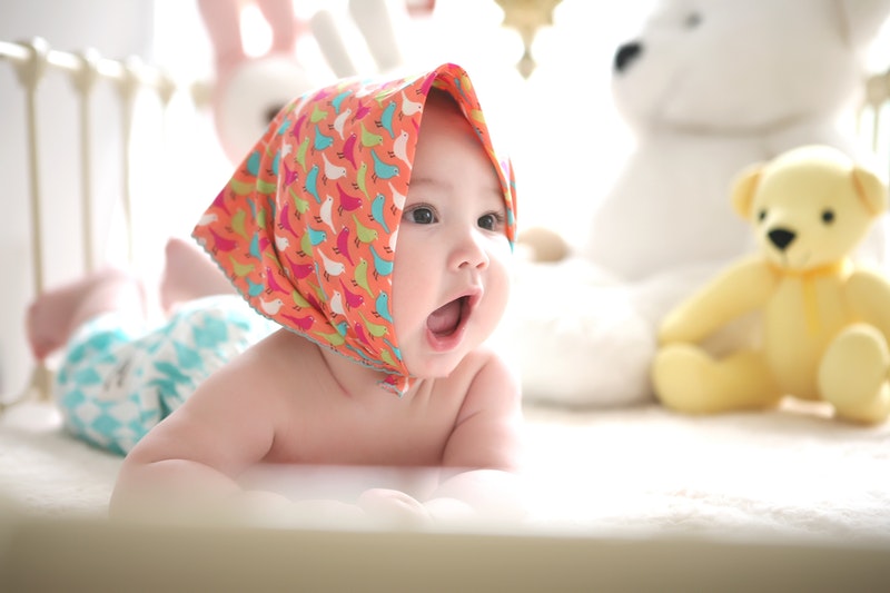 Baby on tummy with headscarf and mouth open