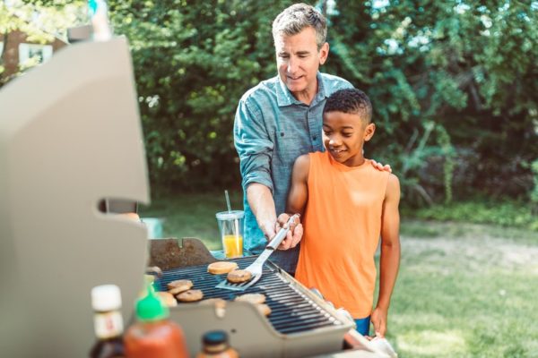 Dad teaching his son to grill