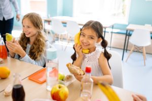 Girl Eating Sandwich with Friends at Table Food Desert