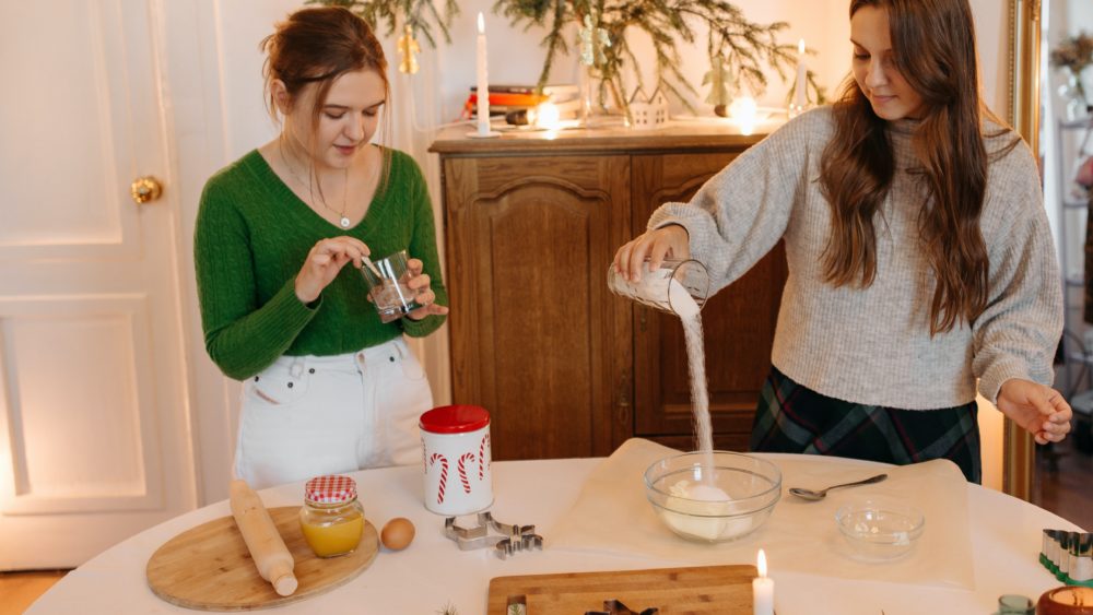 guía de cocina festiva - Dos niñas preparando ingredientes para hornear galletas navideñas