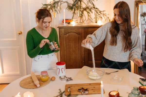 guía de cocina festiva - Dos niñas preparando ingredientes para hornear galletas navideñas