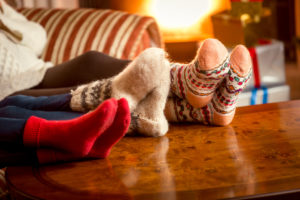Winter Safety Mini: guía, en casa, toma conceptual de primer plano de la familia calentándose los pies en la chimenea