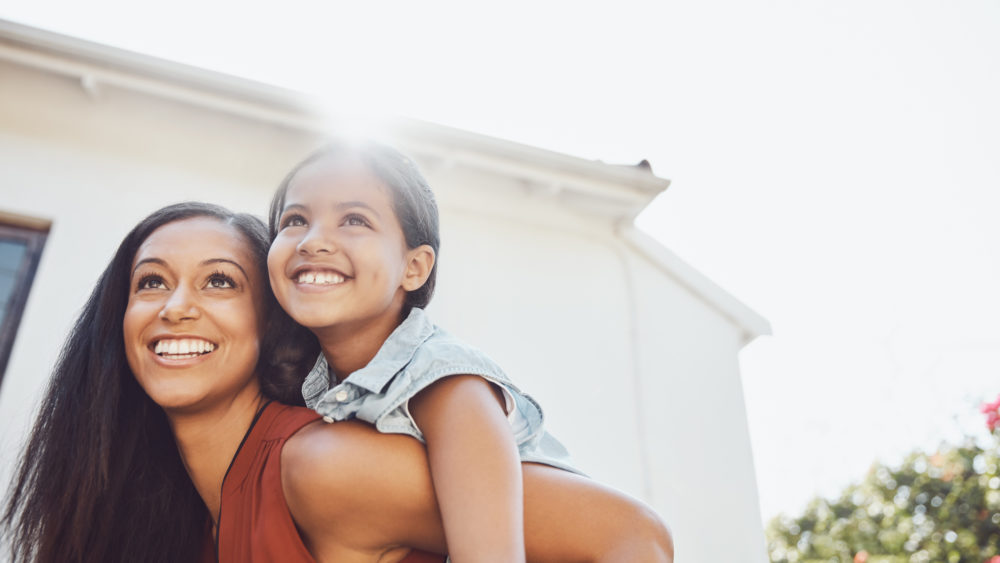 Mental Health in Hispanic Communities | Shot of a happy mother and daughter enjoying a piggyback ride together outdoors